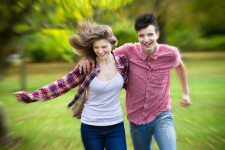 Teenage couple running in parkの写真素材