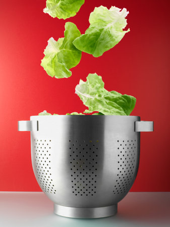 Salad leaves falling into colanderの写真素材