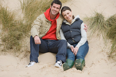 Couple sitting on a sand duneの写真素材