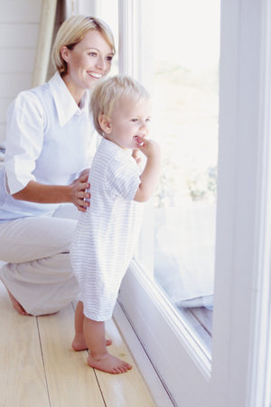 Toddler and mum looking out a windowの写真素材