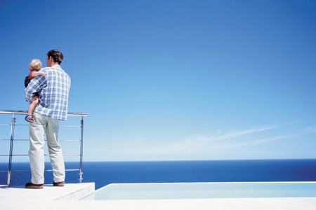 Father holding toddler enjoying a view of the seaの写真素材