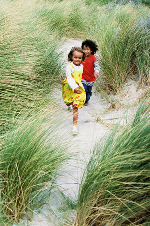 Boy and girl playing on a beachの写真素材