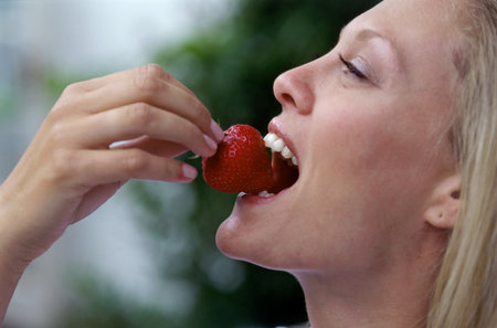 Girl eating strawberryの写真素材