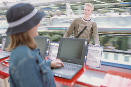 Teenagers looking at laptops in shopの写真素材