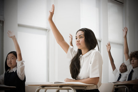 School students with hands raisedの写真素材