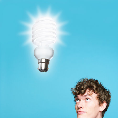A young man looking at an energy saving lightbulbの写真素材