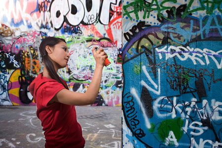 A young woman spraying graffiti
