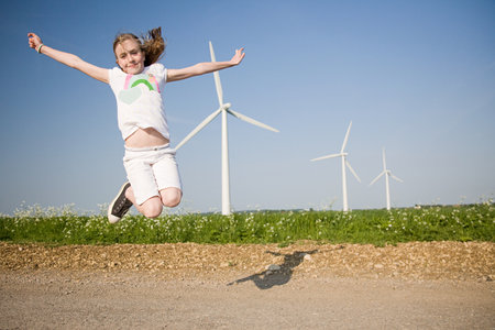 Girl  jumping near wind farmの写真素材