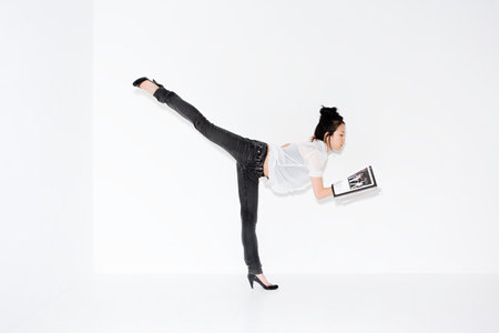 Woman on one leg with magazineの写真素材