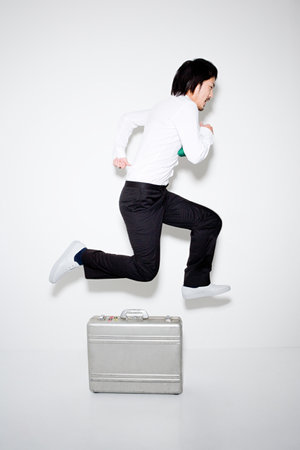 Man jumping over briefcaseの写真素材