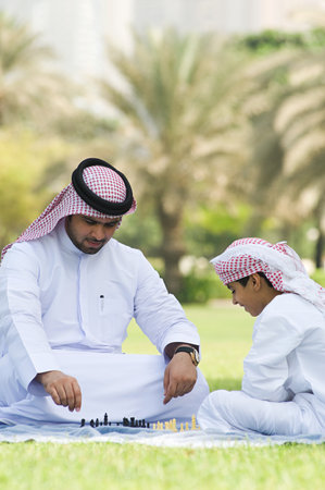 A father and son playing chess in a park