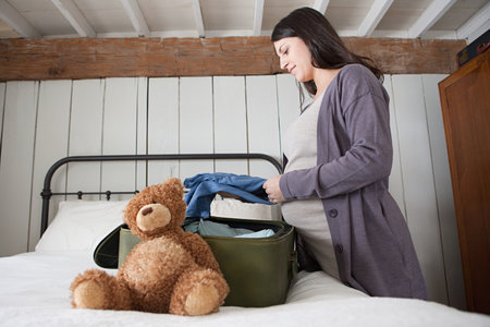 Expectant mother packing suitcase