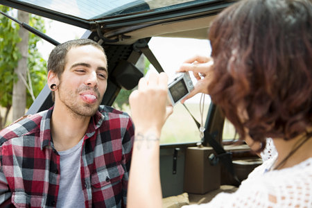 Woman taking picture of man sticking out tongue