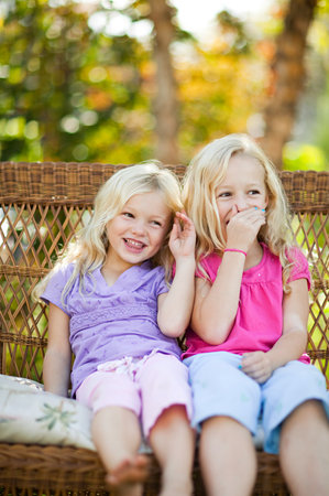 Sisters sitting on seat in gardenの写真素材