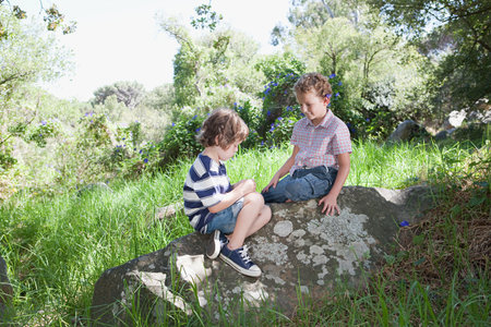 Two boys sitting on a rockの写真素材