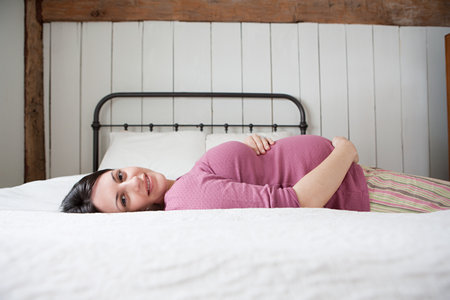 Pregnant woman lying on bedの写真素材
