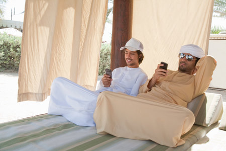 Two Middle Eastern men sitting on bedの写真素材