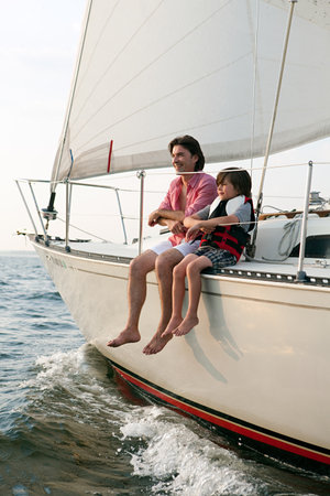 Father and son sitting on yachtの写真素材