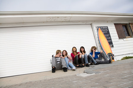 Friends sitting on floor with surfboardの写真素材