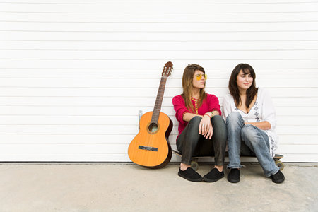 Two girls sitting on floor with guitarの写真素材