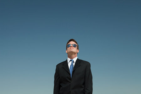 Businessman wearing sunglasses and looking up