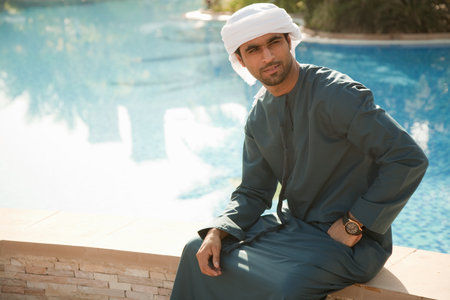 Middle Eastern man sitting by swimming pool, portrait