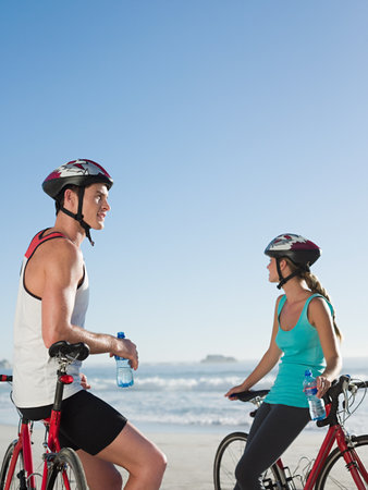 Young couple cycling at beachの写真素材
