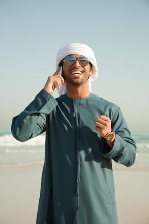 Middle Eastern man using mobile phone on the beachの写真素材