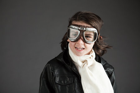 Young boy wearing flying goggles, dressed as pilot