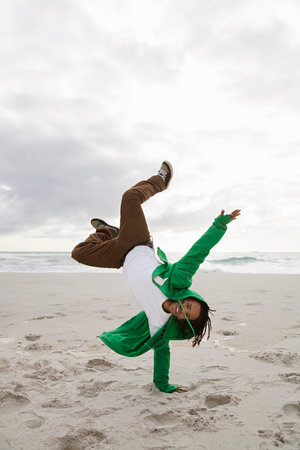 Young man doing cartwheels on beachの写真素材