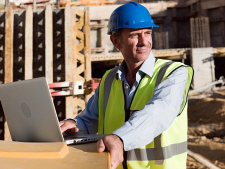 Mature man uusing laptop on construction site