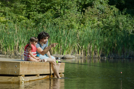 Father and daughter fishing from jettyの写真素材
