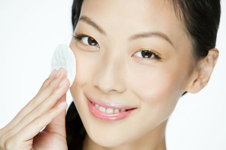Young woman using cotton pad on faceの写真素材