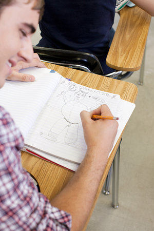 Male high school student doodling in notebookの写真素材
