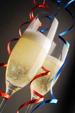 Two champagne glasses with red and blue streamersの写真素材