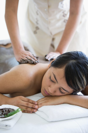 Young woman having mud mask applied to backの写真素材