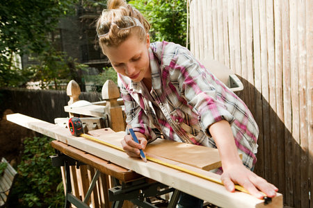 Woman measuring plank of woodの写真素材