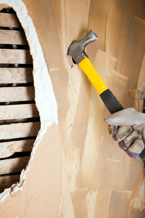 Man knocking hole in wall with hammerの写真素材