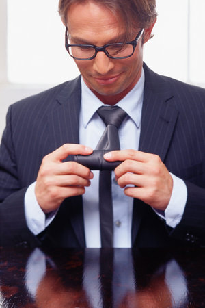 Businessman rolling-up his tieの写真素材