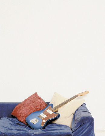 An electric guitar an a blue velvet sofaの写真素材