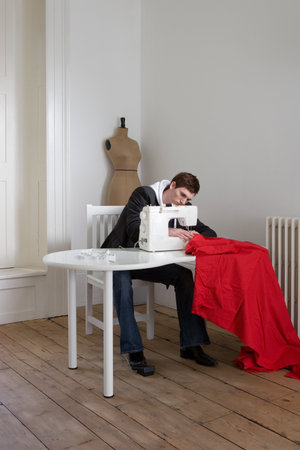 Man sewing red fabricの写真素材