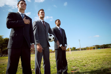 Businessmen standing in row in fieldの写真素材