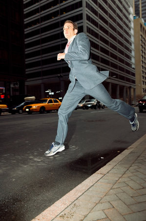 Businessman running through cityの写真素材