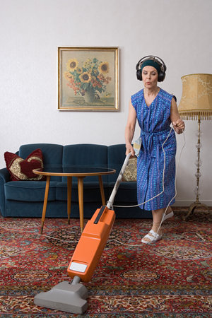 Woman wearing headphones and vacuumingの写真素材