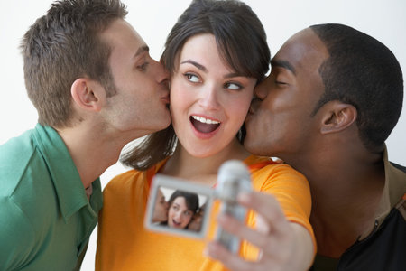 Men kissing woman with video cameraの写真素材