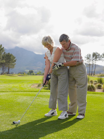 Man giving woman a golf lessonの写真素材