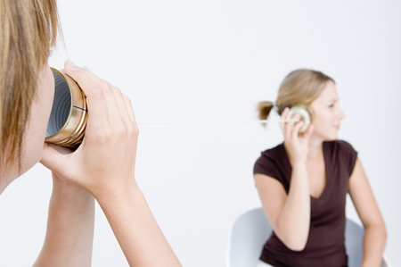 Women using tin can telephoneの写真素材