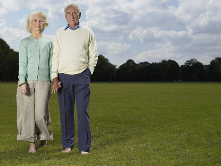 Elderly couple holding hands in parkの写真素材