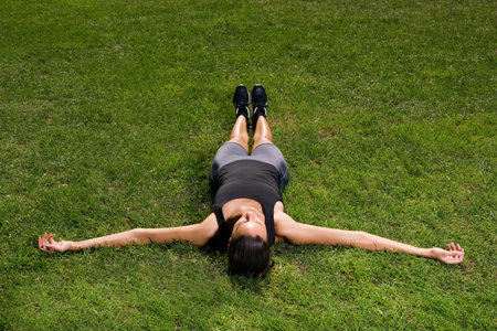 Female athlete lying on the grassの写真素材