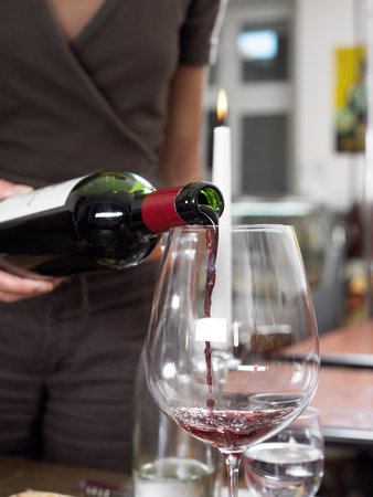 Pouring red wine into glassの写真素材